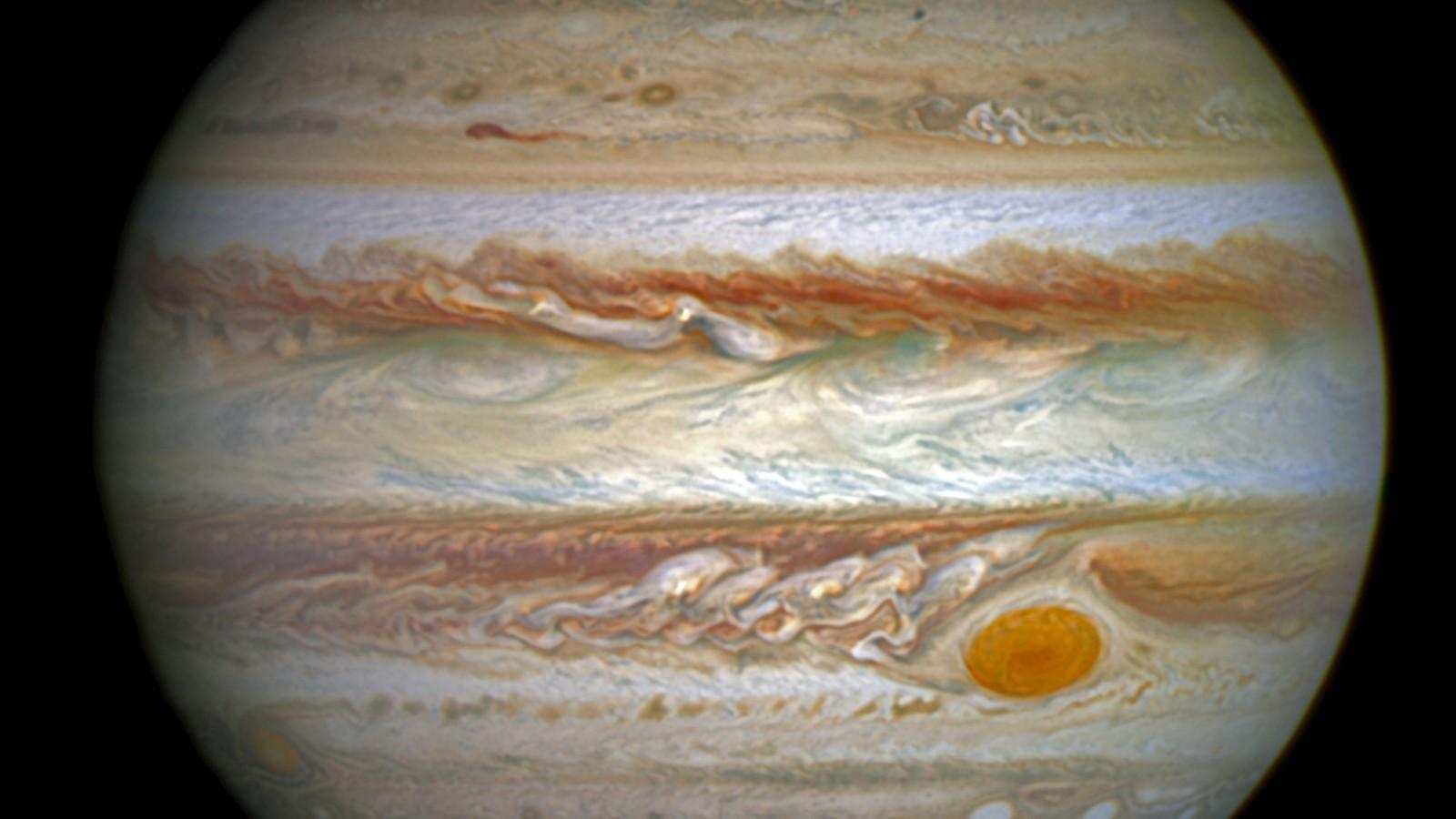 Imagen ultravioleta de Júpiter tomada por el telescopio Hubble: dos vistas del planeta sobre fondo negro, donde la aurora dibuja un anillo azul luminoso alrededor de los polos.