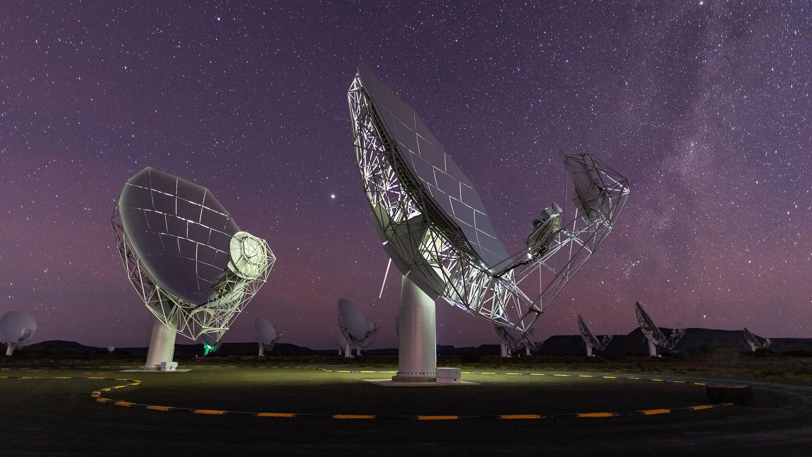 Vista aérea de decenas de antenas parabólicas blancas de la red MeerKAT alineadas en la llanura semiárida del Cabo Septentrional, en Sudáfrica.