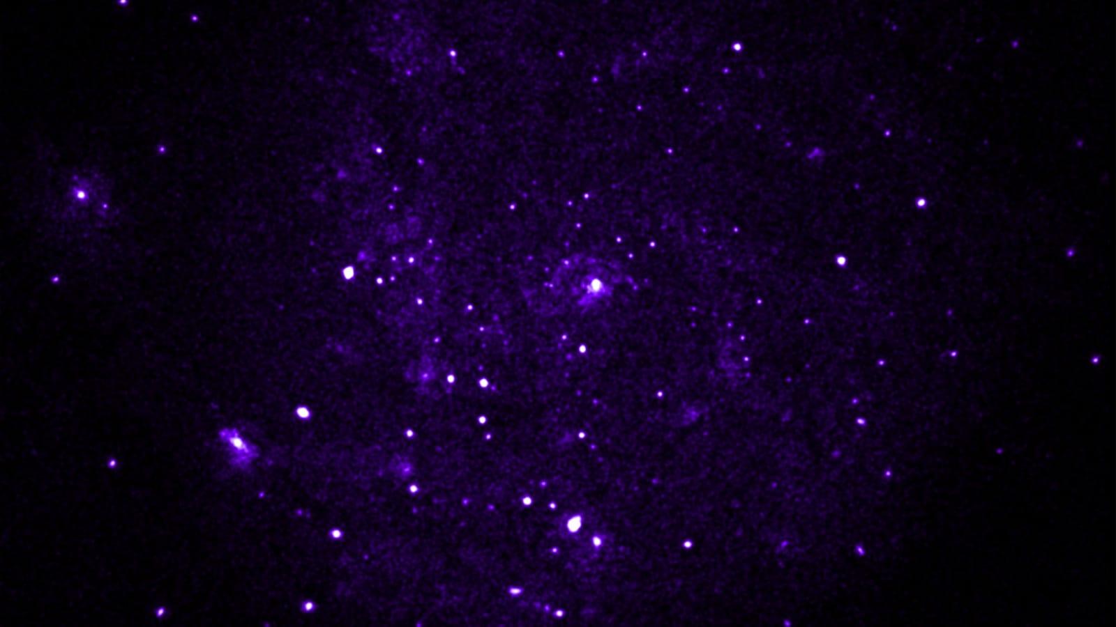 The Pinwheel galaxy seen only in soft X-rays, with bright points scattered over a diffuse purple background.