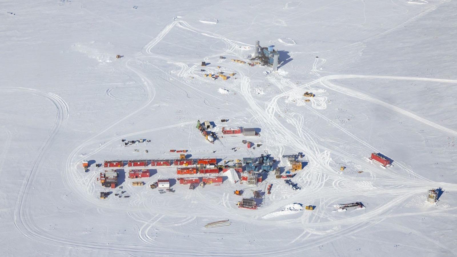 Vista aérea de la base del polo Sur y del campo de sondeos de IceCube, con las cuerdas de sensores alineadas sobre el hielo y las instalaciones del laboratorio.