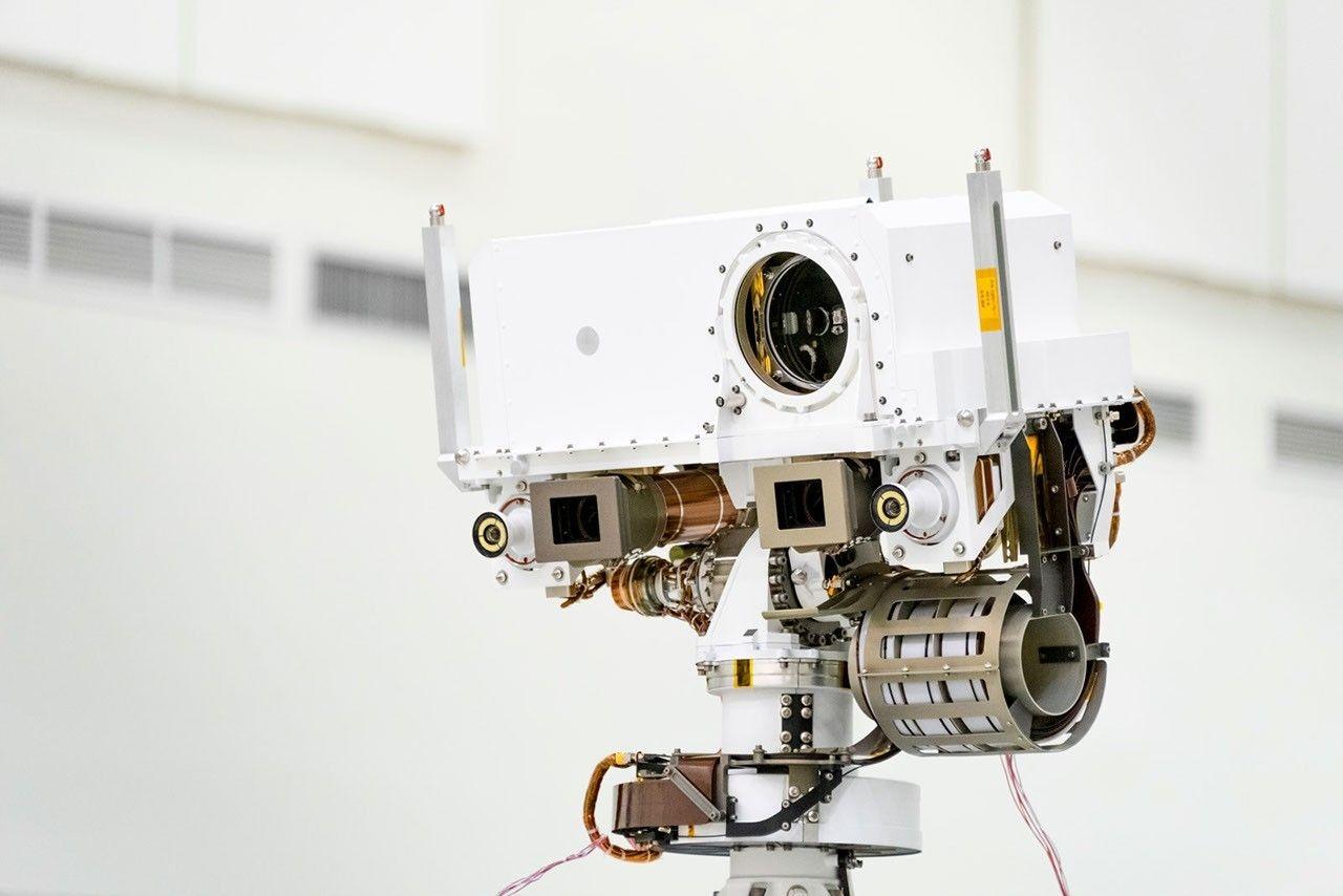 Close-up of the head of the Perseverance rover's remote sensing mast: SuperCam's round lens in the centre, flanked and framed by the Mastcam-Z camera boxes and the navigation cameras.