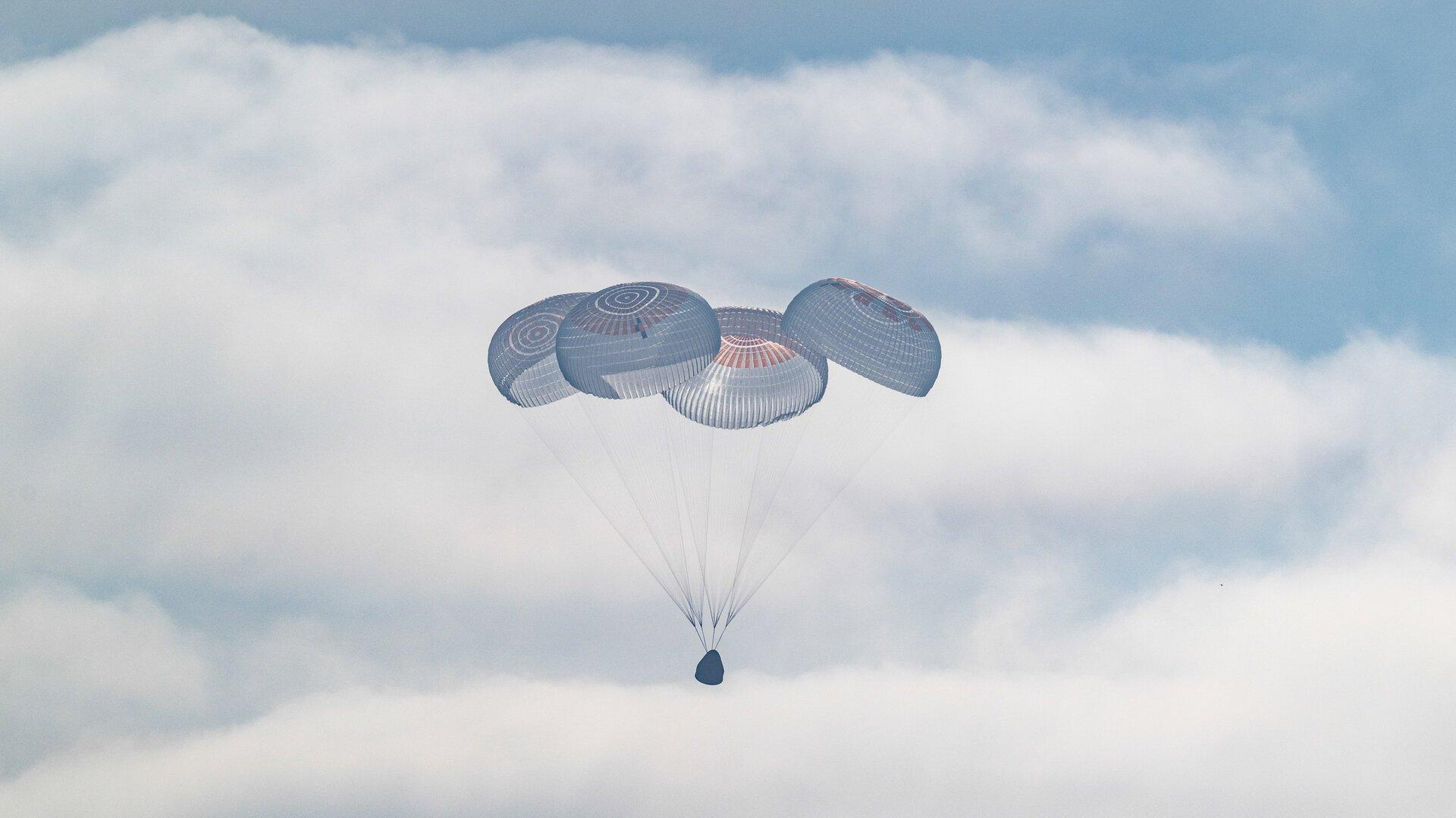 The SpaceX Crew Dragon Freedom capsule resting on the Pacific Ocean off the coast of California, surrounded by recovery boats, after the Crew-12 splashdown.
