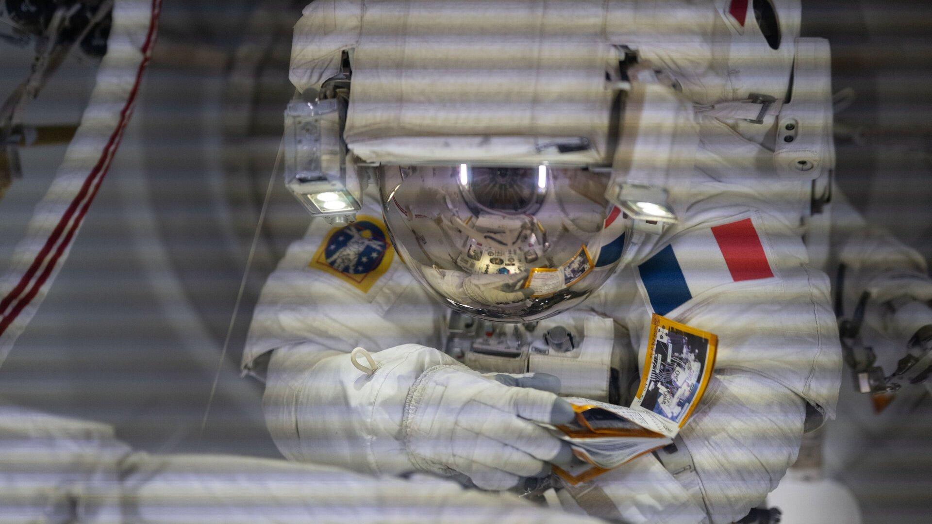 Astronaut Sophie Adenot, in a spacesuit with her helmet open, works outside the International Space Station during the EVA-99 spacewalk.