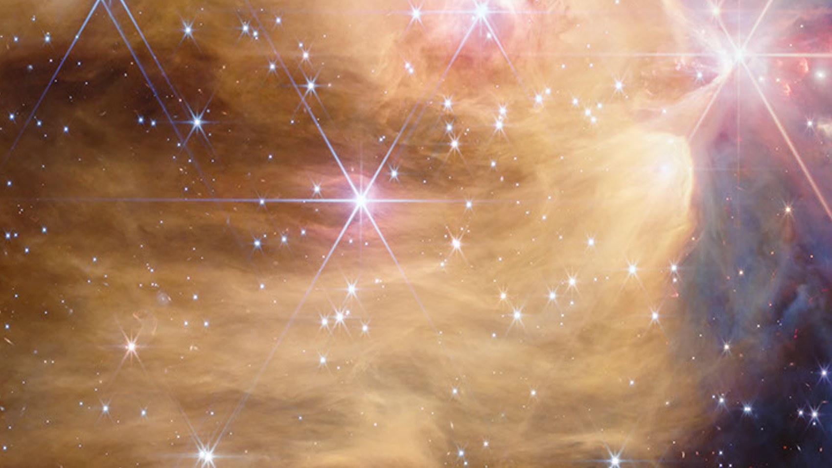 Close-up of the golden cavity of NGC 7129: a vast lobe of luminous golden hydrogen dotted with blue stars, its upper edge forming a sharp ridge.