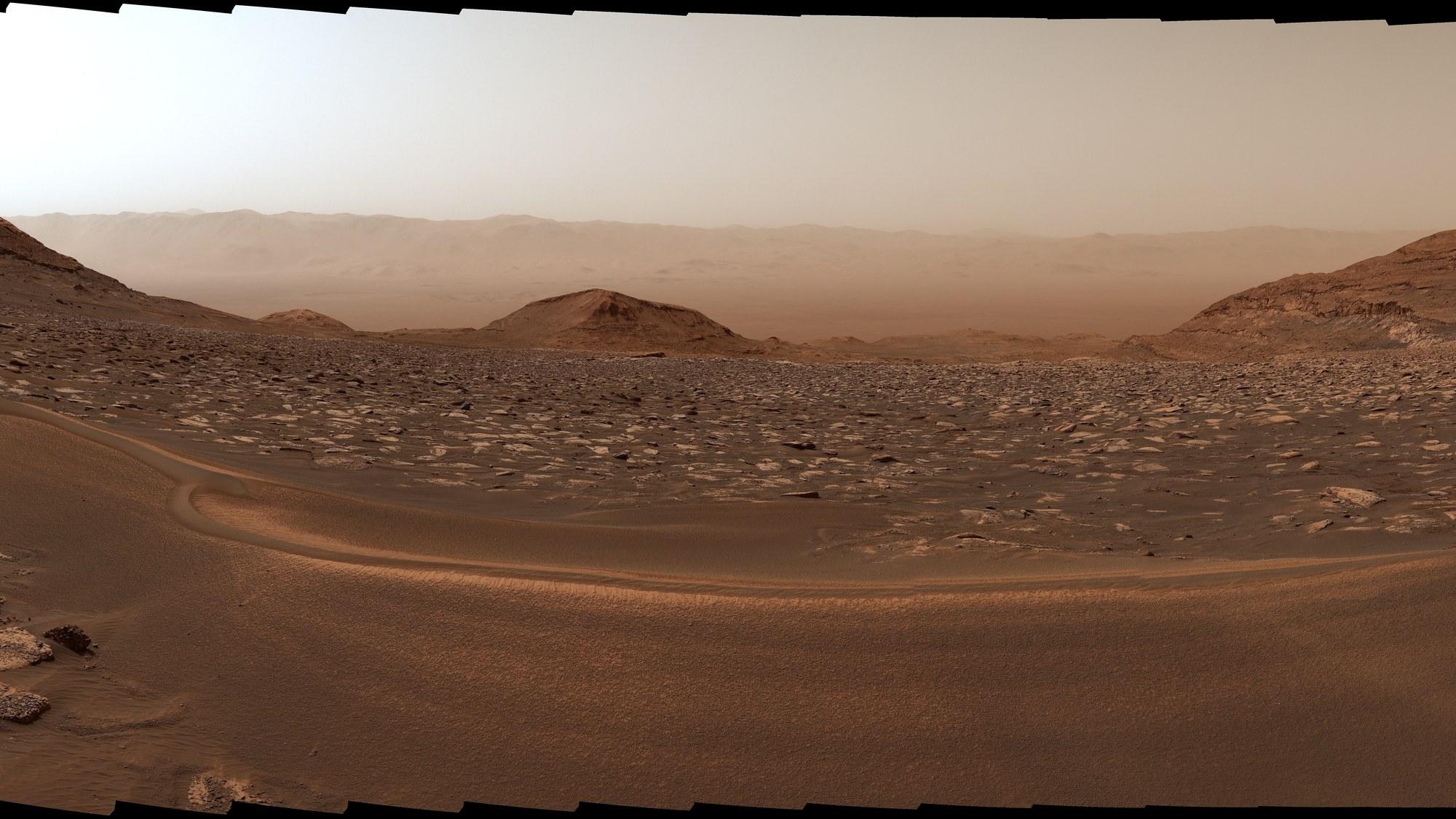 Vista hacia abajo del fondo del cráter Gale, fotografiada por Curiosity: una vasta cuenca rocosa y polvorienta se extiende hasta el horizonte desde la ladera del Monte Sharp.