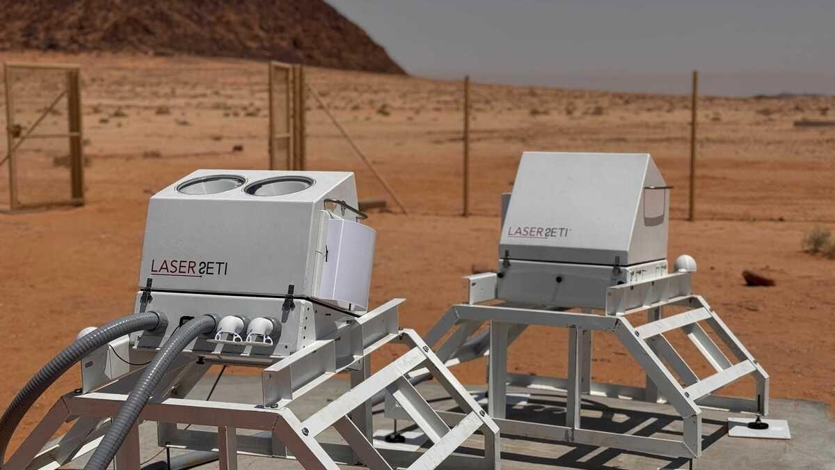 Two LaserSETI stations, made of metal enclosures and cameras, installed on the desert plateau of AlUla Manara in Saudi Arabia.