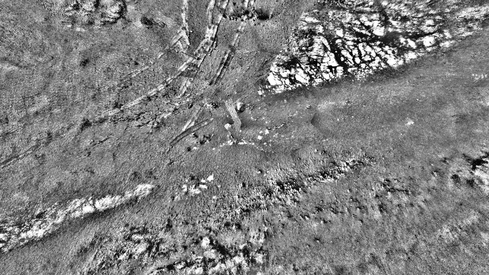Mosaïque d'images de la caméra de navigation d'Opportunity : un sol clair et caillouteux où deux profondes traces parallèles de roues, larges d'environ 1 mètre, creusent la poussière rouge et dessinent une courbe vers l'horizon.