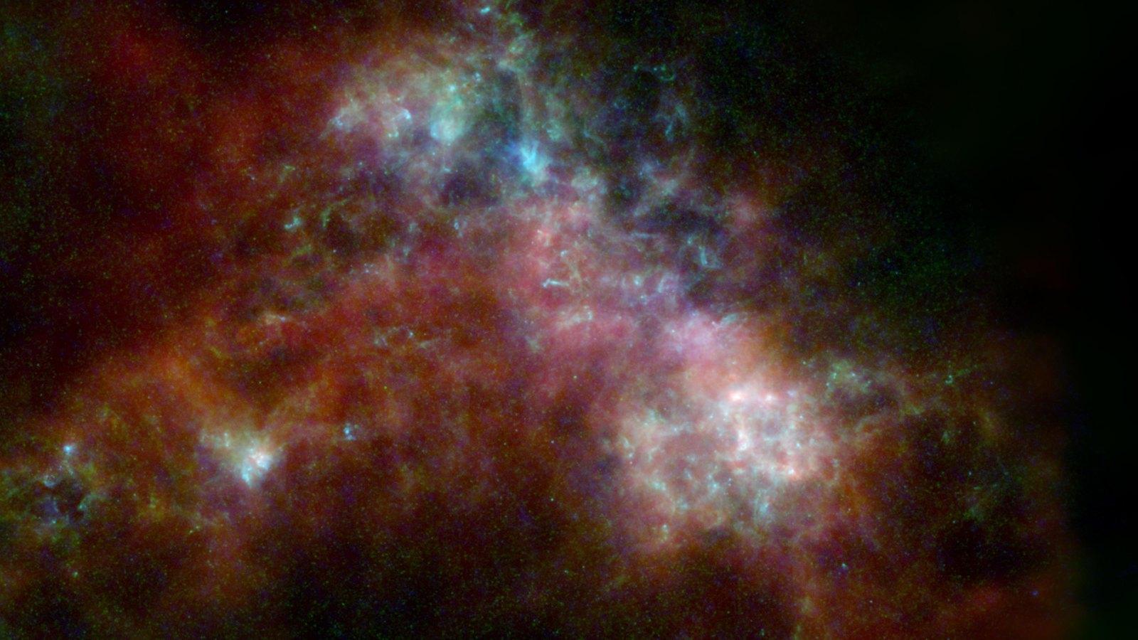Le Petit Nuage de Magellan vu dans l'infrarouge lointain : une vaste nébuleuse de poussière aux teintes bleues et rouges, où le bleu marque la poussière la plus chaude et le rouge la plus froide.