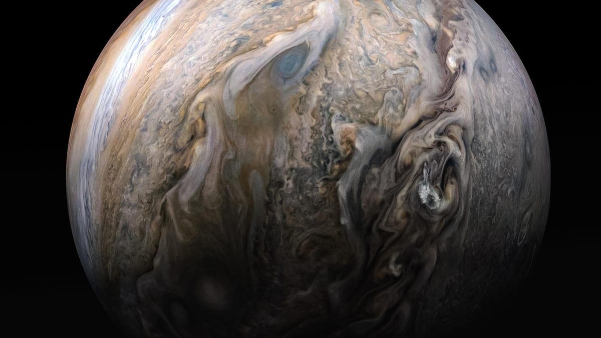 Imagen de Júpiter tomada por la sonda Juno: un mosaico del hemisferio norte con bandas de nubes turbulentas, vórtices blancos y nubes brillantes que asoman a gran altitud.