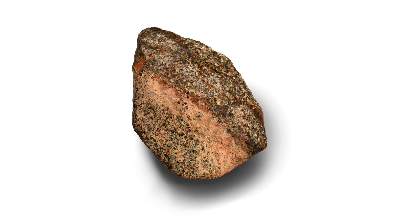 The Martian meteorite Teghaza 001, an 800-gram rock with a rose tint, photographed in close-up against a white background.