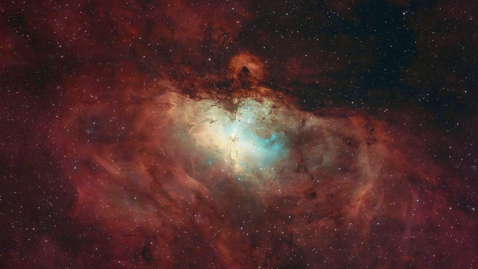 La nebulosa del Águila fotografiada por el telescopio Atlas: pilares oscuros de gas y polvo recortados sobre un fondo rosado y azulado de estrellas.
