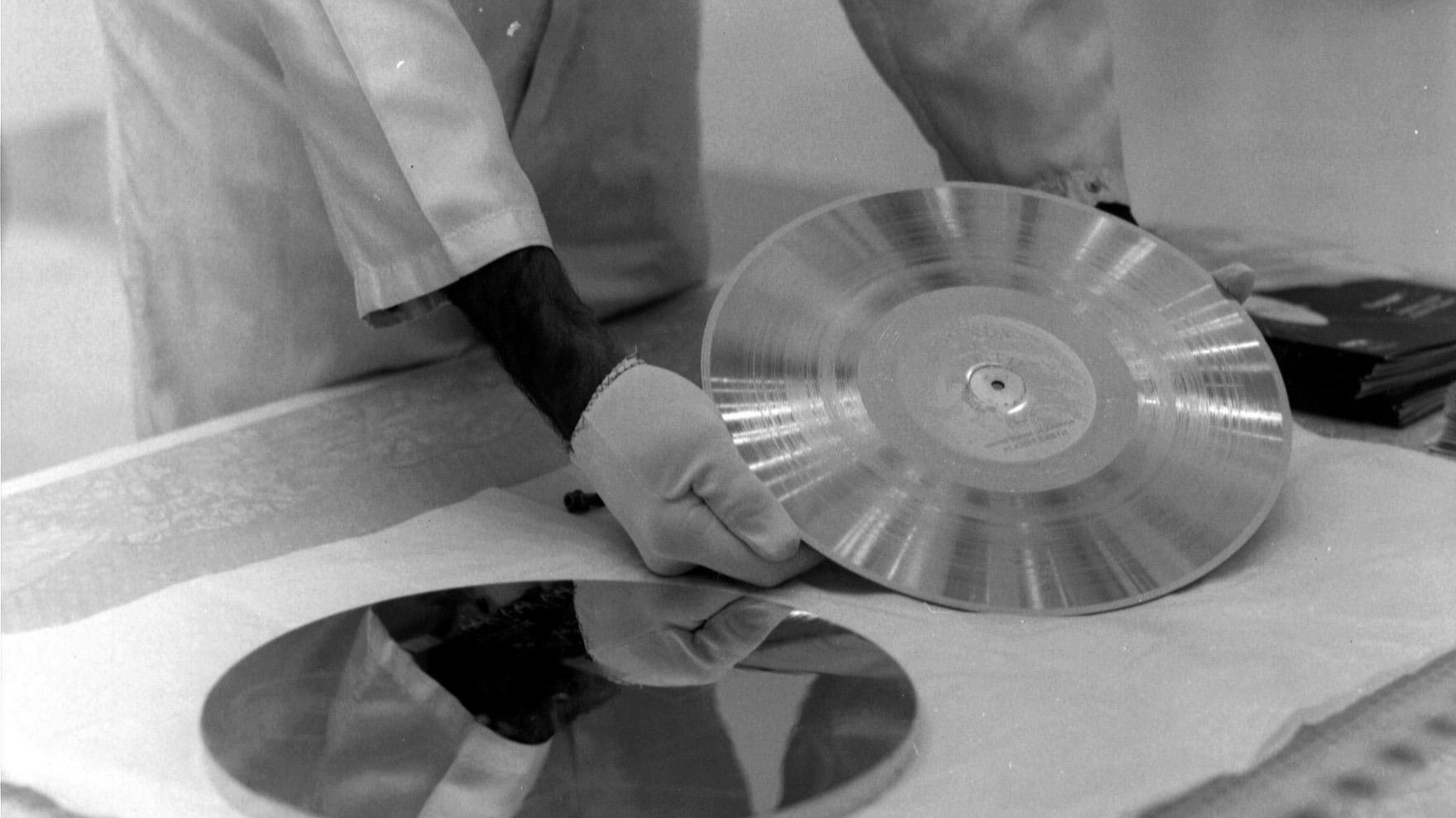Un ingénieur de la NASA ajuste la couverture de protection du disque d'or embarqué à bord de Voyager, avant le lancement de 1977.